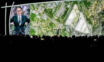 トヨタ自動車の当時社長だった豊田章男がCES2020のステージで、聴衆の前でWoven Cityのコンセプトを公開している写真