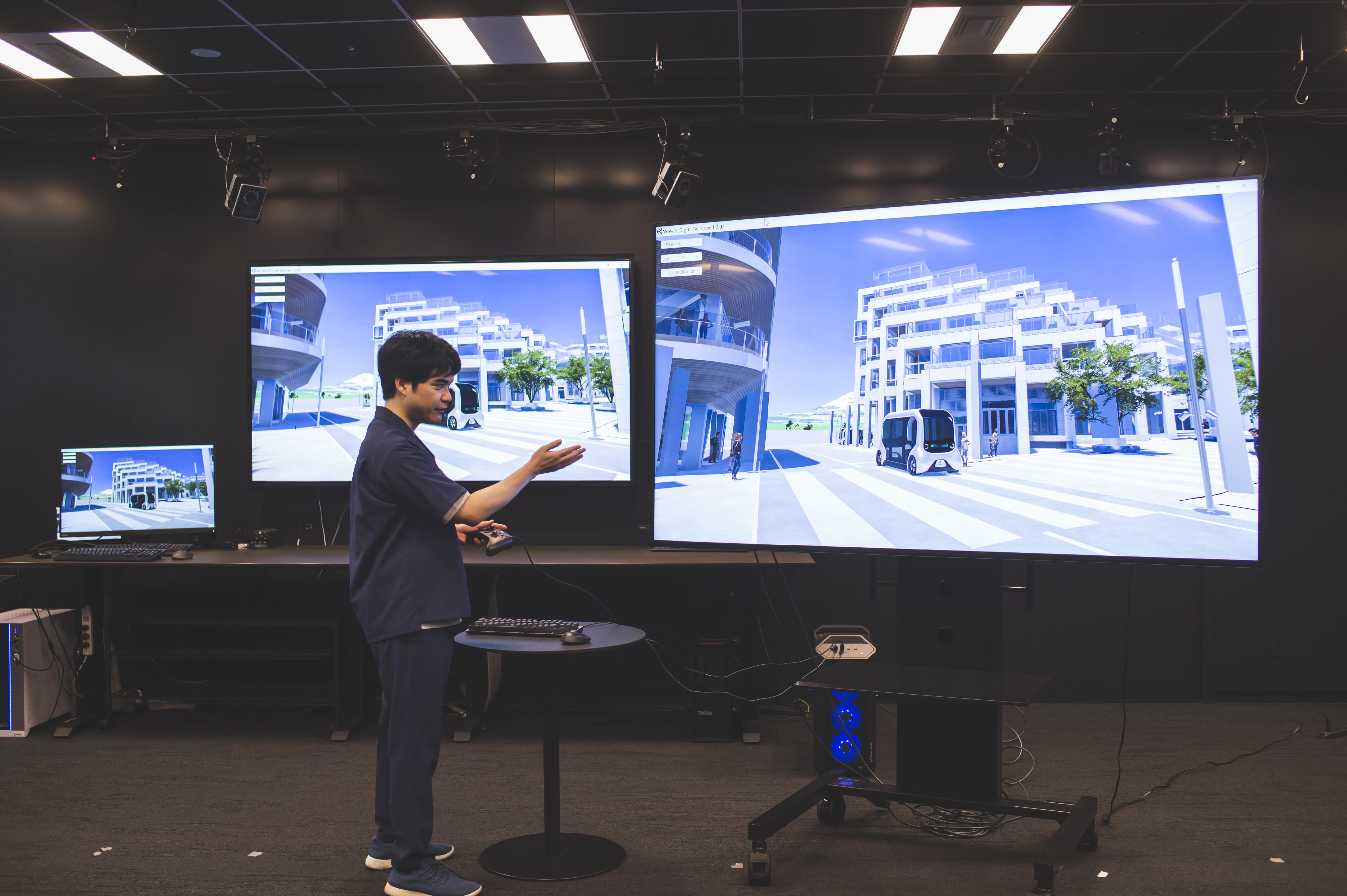 ウーブン・バイ・トヨタ小嶋さんがデジタルツインのWoven Cityの映るモニターの前で話している様子の写真