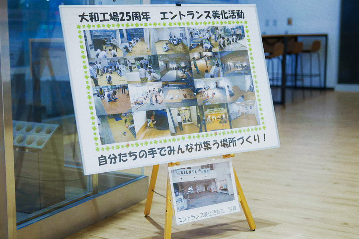 Photo of the entrance of the Toyota Motor East Japan Miyagi Taiwa Plant where a panel is displayed with a collection of photos of employee-led DIY projects